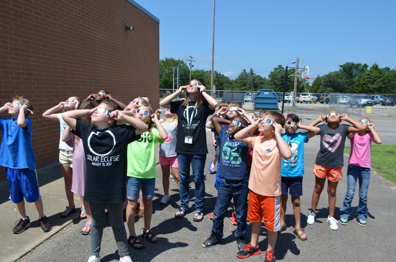 Third Grade students look at the solar eclipse with their teacher.